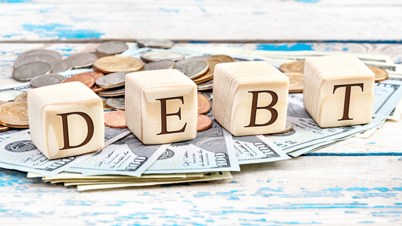 blocks spelling out debt on top of piles of money