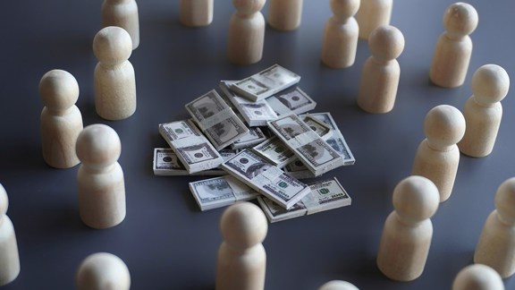 wooden people around pile of money that they raised