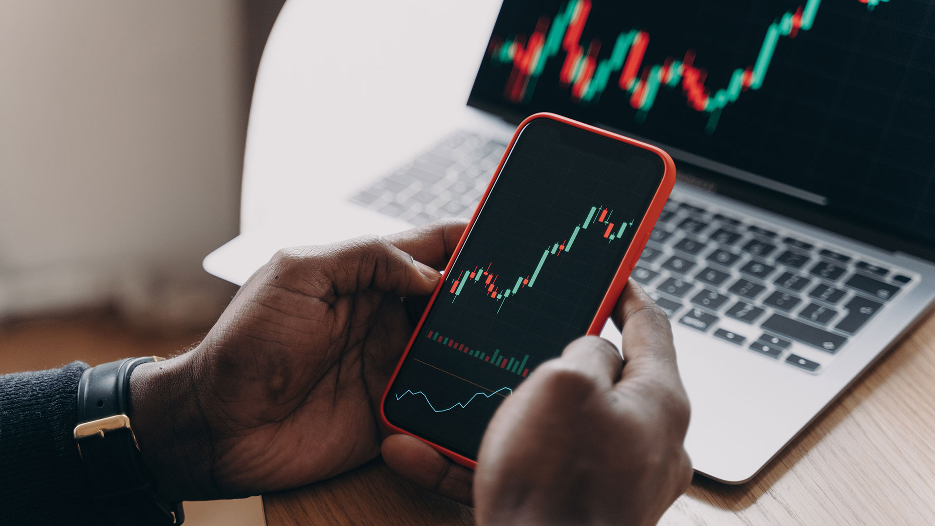 person on the stock market on phone and laptop